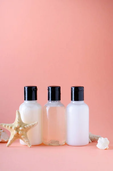 Botellas cosméticas sobre fondo con color de coral vivo. Composición de botellas de champú, acondicionador y loción corporal . — Foto de Stock