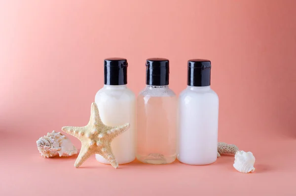 Botellas cosméticas sobre fondo con color de coral vivo. Composición de botellas de champú, acondicionador y loción corporal . — Foto de Stock