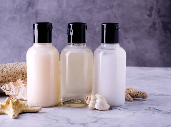 Frascos cosméticos sobre fondo gris Composición de frascos de champú, acondicionador y loción corporal . — Foto de Stock