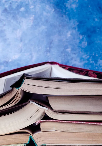 Stack of books piled against blue background. School concept. — Stock Photo, Image