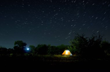 Yıldızdolu güzel bir gece gökyüzünün altında kamp çadırı. Işıklı turistik çadırın üzerinde yıldızlı gece gökyüzü.