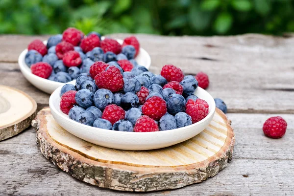 Still life with a blueberries and raspberries on an old wooden table, at the garden. Rural natural food style. — Stock Photo, Image
