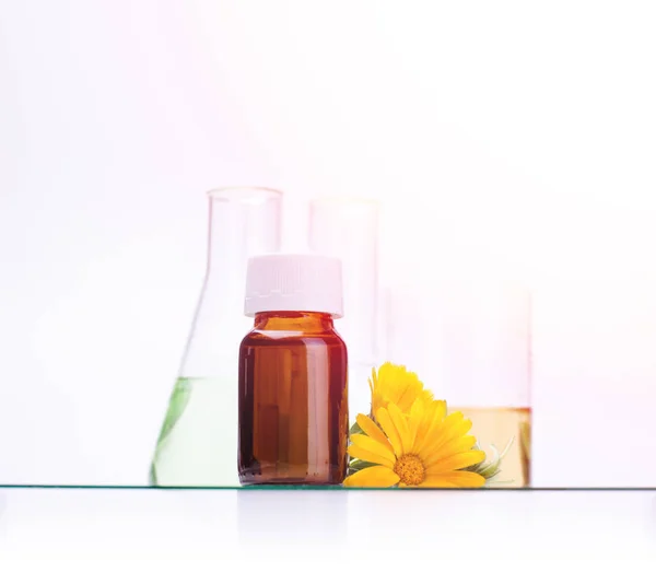 Dark cosmetic bottle of aromatic oil for herbal medicine with calendula flower isolated on white backdrop. Marigold extract. — Stock Photo, Image