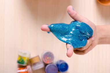 Çocuk el parlak glitter balçık tutan. Çocuk balçık ile oynarken, dünya çapında popüler kendini oyuncak yaptı.