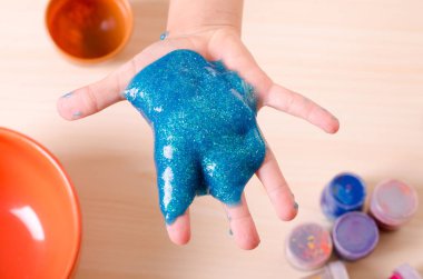 Çocuk el parlak glitter balçık tutan. Çocuk balçık ile oynarken, dünya çapında popüler kendini oyuncak yaptı.