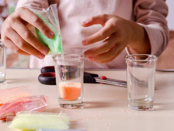 Making candles by yourself process. Little girl making candle in the glass from soy wax parsley flakes.