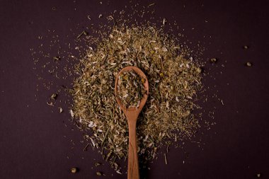 Koyu bir arka planda, tahta kaşıkta papatya çayı..