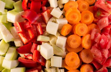 Dilimlenmiş sebzeleri tahta kesme tahtasıyla kapat. Havuç, domates ve kabak dilimleri. Yiyecek malzemeleri.