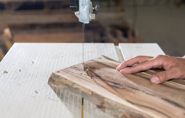 Close up Carpenter hands working on band saw with wooden shape to create interior products.