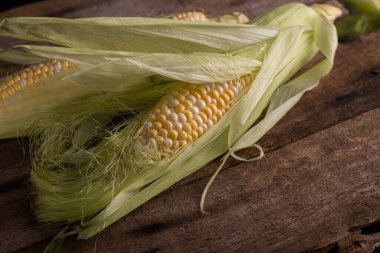 Eski ahşap bir masada taze çiğ mısır. Sonbahar hasadı hala karanlık bir ruh hali içinde..