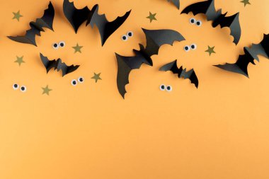 Cadılar Bayramı şablonu siyah kağıt yarasalar ve renkli sarı bir arka planda plastik ürkütücü gözler..