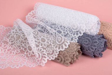 Roll of Delicate color laces for panties and bras on pink background with plastic fittings. Elastic material. Using for Atelier and fabric store.