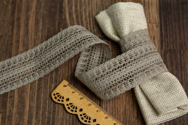 knitted beige openwork linen ribbon tapes in rural style of rustics cotton eco natural on wood ground