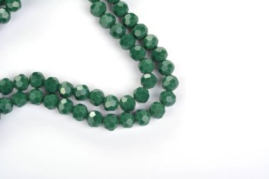 Beyaz arka planda parlak yeşil cam kristal boncuklar. Küçük boncuklu mücevherler için kullan