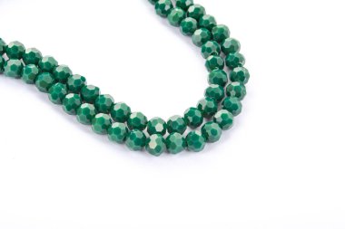 Beyaz arka planda parlak yeşil cam kristal boncuklar. Küçük boncuklu mücevherler için kullan