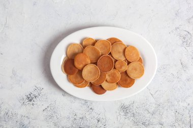 Modaya uygun ev yapımı kahvaltı, krep gevreği, beyaz tabakta beyaz beton arka planda mini krepler.