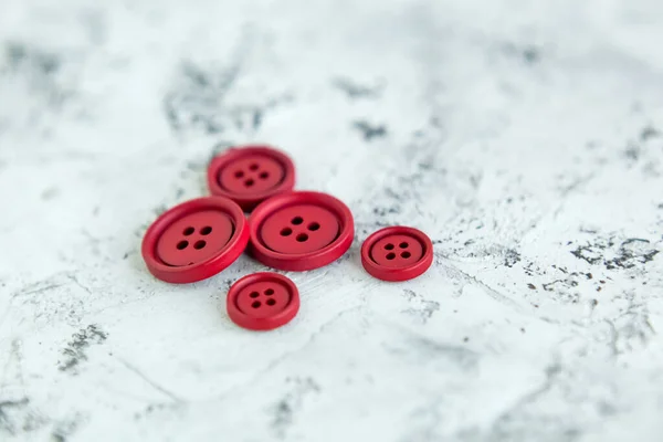 Pile of red matte buttons on concrete background, macro bokeh. beautiful needlework