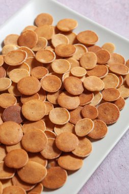 Modaya uygun ev yapımı kahvaltı, krep gevreği, pembe beton arka planda hafif tabakta mini krep.