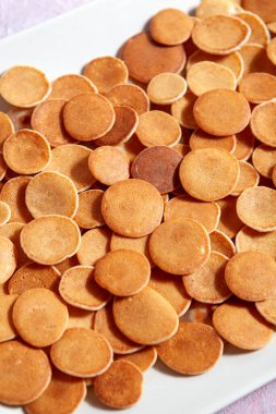 Modaya uygun ev yapımı kahvaltı, krep gevreği, pembe beton arka planda hafif tabakta mini krep.