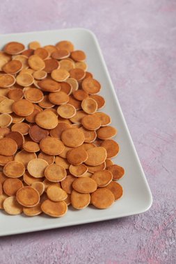 Modaya uygun ev yapımı kahvaltı, krep gevreği, pembe beton arka planda hafif tabakta mini krep.