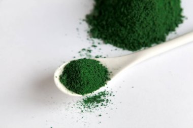 Beyaz kaşık klorella ya da spirulina yosunlu ya da matcha, açık arkaplanlı. Süper yiyecek konsepti tozu.