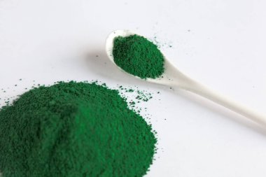 Beyaz kaşık klorella ya da spirulina yosunlu ya da matcha, açık arkaplanlı. Süper yiyecek konsepti tozu.