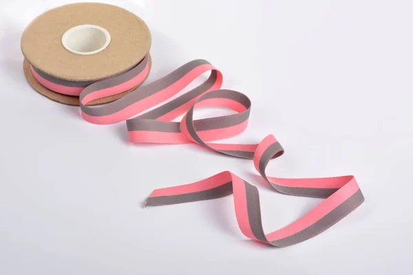 ピンクとグレーのコットンリボン ボビンにロールテキスタイル テープとロープをはがす Lime白い背景にカールをつけたウェビング バッグ ストラップの縫製に使用します テキストのスペース — ストック写真