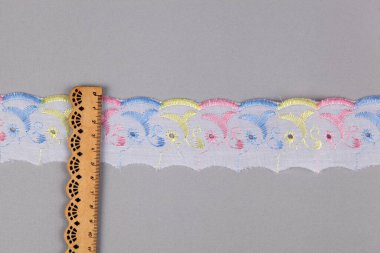 düz renkli pamuk şerit işlemeli ve gri arka planda ahşap cetvel. Dikiş dikmek için ulusal model. desen ve birbirine dokuma iplikleri. Web siteleri için doku. Metin için boşluk.