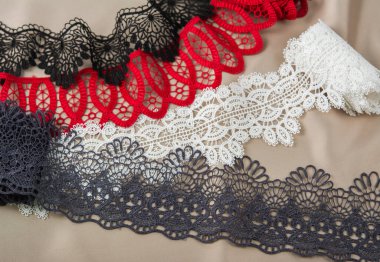 Bir yığın kırmızı, beyaz. Siyah ve gri, lüks, kaliteli, bej arka planda dantel kumaş. Elbise dikmek için keten süsleme için kullanılır. Web siteleri için doku