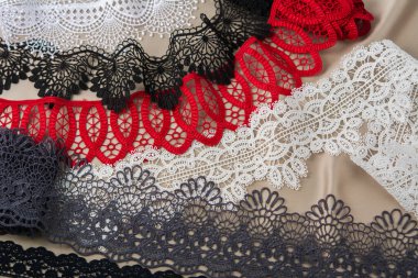 Bir yığın kırmızı, beyaz. Siyah ve gri, lüks, kaliteli, bej arka planda dantel kumaş. Elbise dikmek için keten süsleme için kullanılır. Web siteleri için doku