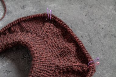 Kahverengi süveter, örgü işleme süreci, beton arka plan. Raglan iğneleri. yün dokuma iplikleri.