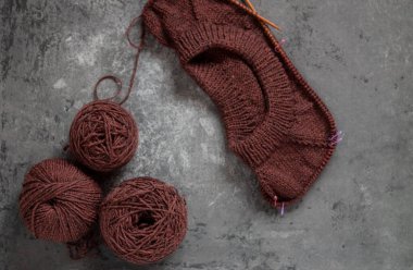 Kahverengi süveter, örgü işleme süreci, beton arka plan. Raglan iğneleri. yün dokuma iplikleri.