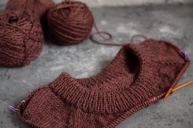 Kahverengi süveter, örgü işleme süreci, beton arka plan. Raglan iğneleri. yün dokuma iplikleri.