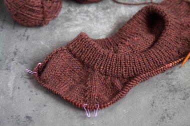 Kahverengi süveter, örgü işleme süreci, beton arka plan. Raglan iğneleri. yün dokuma iplikleri.