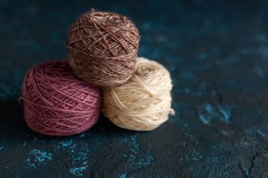 Üç bej pembe kahverengi renkli toplar örgü örmek için yün yumağı ve koyu mavi desenli macun betona örülmüş. Metin için alanı olan düz resim.