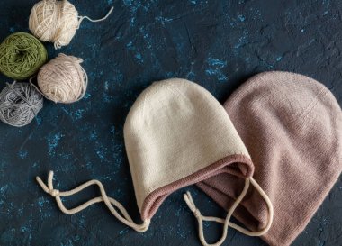 Örgü örmek için yün yumağı, örgü örmek için yün yumağı ve koyu mavi desenli macun beton şapkalar. Metin için alanı olan düz resim.