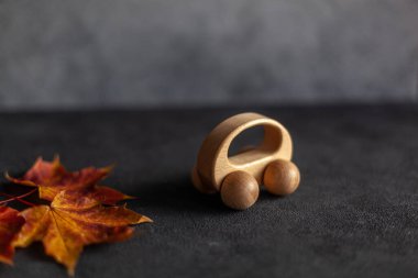 Renkli mermer yaprakların ve gri beton duvardaki ahşap arabanın minimum bileşiminden oluşmuş desen. Autumn konseptini kapat. metin için boşluk kopyala.