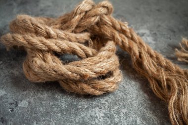 Gri, soyut beton arka planda büyük, hırpalanmış bir halat. Metin için boşluk.