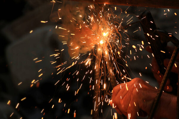 A person works with welding, without protective equipment - gloves and a mask. Welding allows you to reliably connect metal elements during the repair, manufacture of parts.