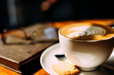 Bir bardak aromatik kahve, telefon ve defter ile bir masada oturan bir adamın eli. İş yemeği