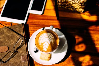 Bir bardak aromatik kahve, telefon ve defter ile bir masada oturan bir adamın eli. İş yemeği