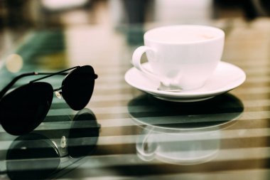 Bir bardak aromatik kahve, telefon ve defter ile bir masada oturan bir adamın eli. İş yemeği