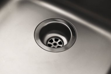 Çelik bir lavaboya yakın çekim. Lavabo temiz, tıkanıklık yok. Su kaynağı.