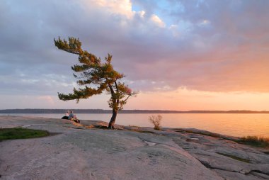 Huzurlu manzara - bulutlar ve yumuşak ışık turuncu ile göl üzerinde kayalık kıyıdan gün batımını izlemek büyük çift pembe. Günbatımı Killbear Provincial Park, Ontario, Kanada