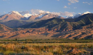 Buzul tepeler ve mavi gökyüzü, Güney kıyı Gölü Issyk Kul, Kırgızistan yumuşak ışıkla gün batımında doğal dağ manzarası.