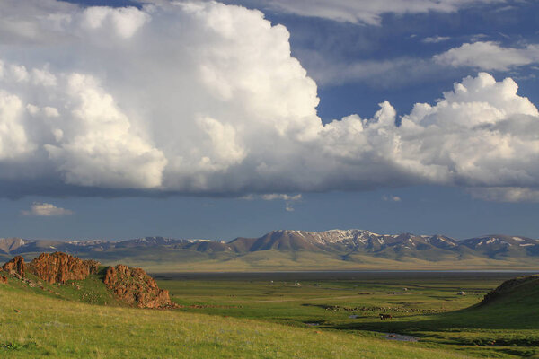 Beautiful landscape - green valley by Song Kul lake, Kyrgyzstan. Sunny day with blue sky and white clouds.