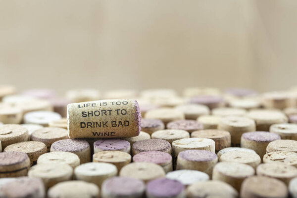 Closeup macro of a cork with sign life is too short to drink bad wine on wine corks mosaic.Soft light, no shadows, selective focus, shallow depth of field with blurred background. Space for copy.