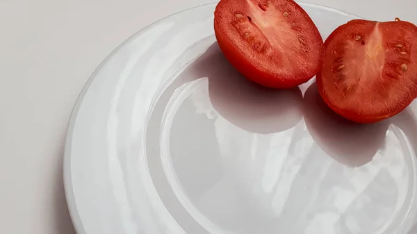 Dos mitades de tomate rojo en un plato blanco sin patrones — Foto de Stock