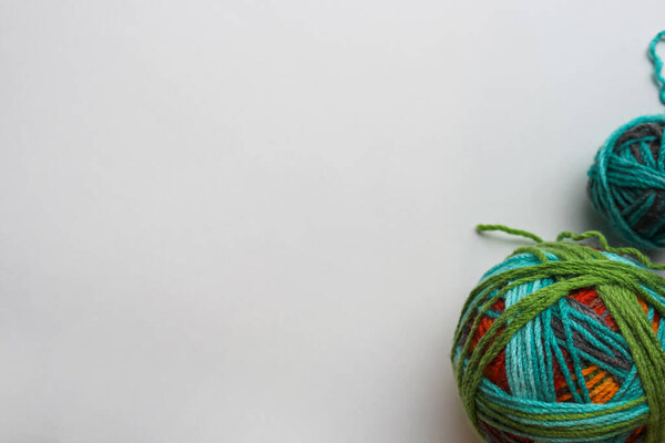 Два шара пряжи разных размеров на белом фоне в углу
