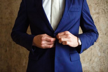 bir adam düğmeleri mavi ceket elinde saati bağlar.